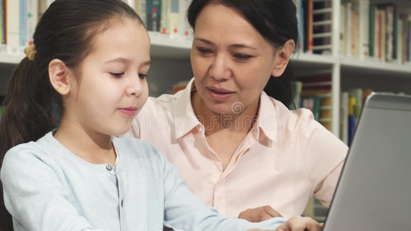 Madre e hija alegres que aprenden en línea con una laptop almacen de metraje de vídeo