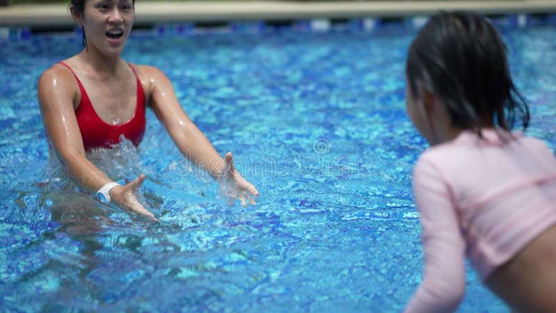 Madre e hija china asiática disfrutando en la piscina con su hija atrapada por la madre almacen de video