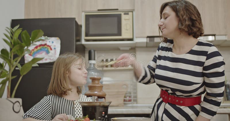 Madre e hija disfrutando de la diversión de la fuente de chocolate en casa : Un dulce trato de tiempo familiar almacen de metraje de vídeo