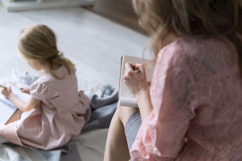 Madre e hija jovenes que ambos blondes se sientan cómodamente y que escriben listas y las metas por el Año Nuevo La mamá escribe imagen de archivo Madre e hija jovenes que ambos blondes se sientan cómodamente y que escriben listas y las metas por el Año Nuevo La mamá escribe imagen de archivo