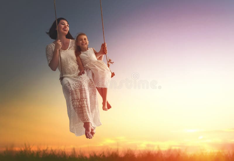 Madre e hija que balancean en oscilaciones imagen de archivo libre de regalías Madre e hija que balancean en oscilaciones imagen de archivo libre de regalías