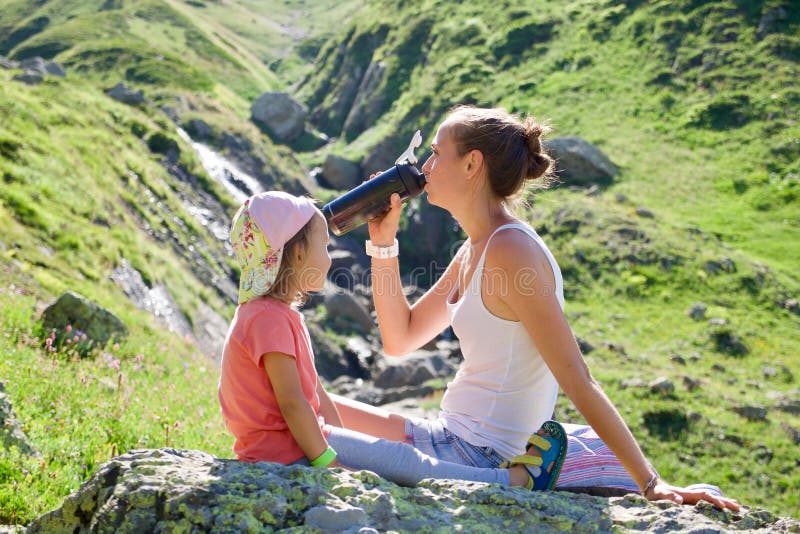 Madre e hija que descansan sobre la piedra grande en la excursión del viaje imagenes de archivo Madre e hija que descansan sobre la piedra grande en la excursión del viaje imagenes de archivo