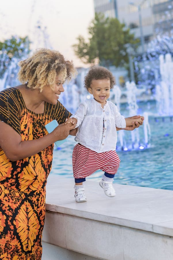 Madre e hija que se divierten con agua de la fuente imagen de archivo