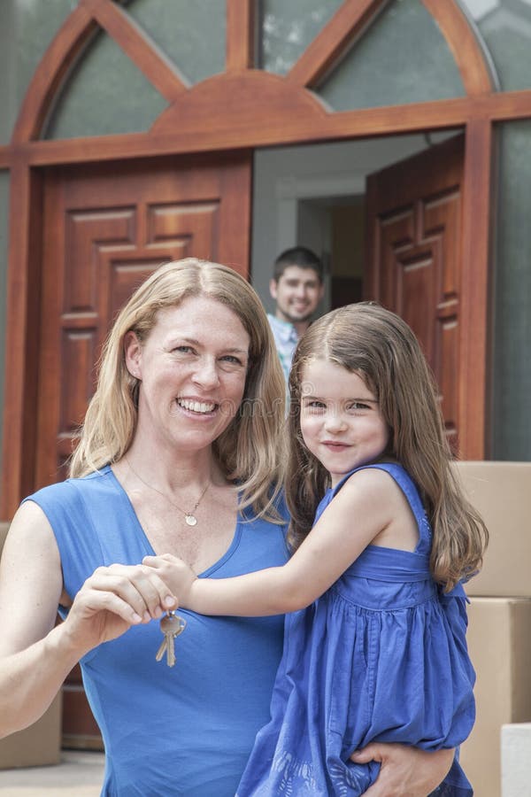 Madre e hija que sonríen y que llevan a cabo las llaves a su nueva casa foto de archivo Madre e hija que sonríen y que llevan a cabo las llaves a su nueva casa foto de archivo