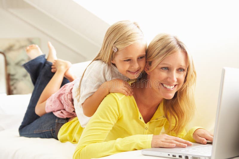Madre e hija que usa la computadora portátil que se relaja en el sofá imagen de archivo libre de regalías Madre e hija que usa la computadora portátil que se relaja en el sofá imagen de archivo libre de regalías