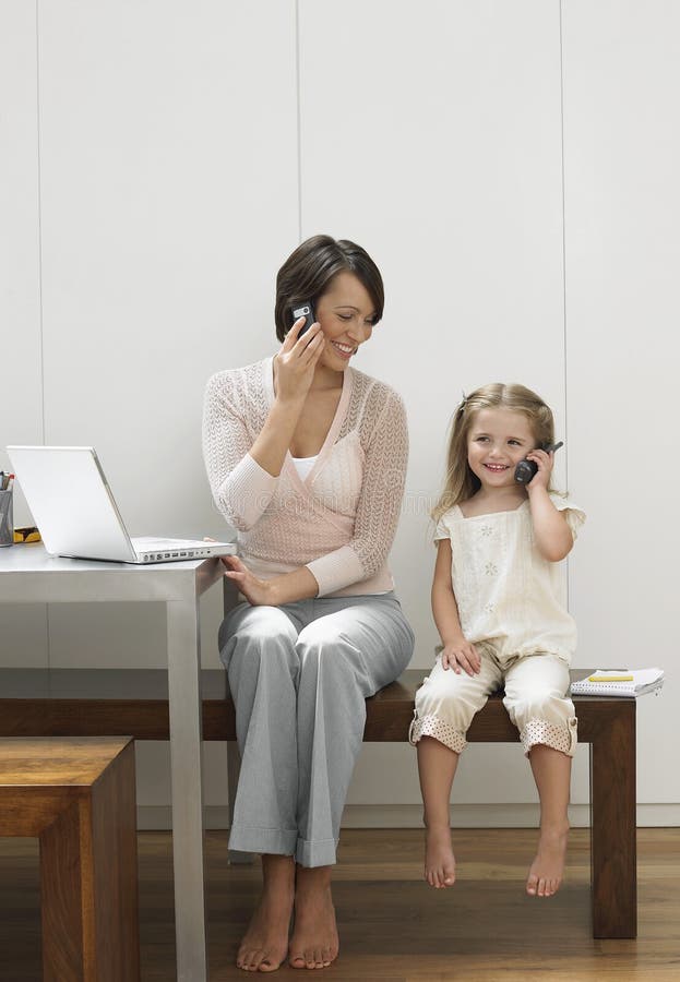 Madre e hija que usa los teléfonos móviles foto de archivo libre de regalías Madre e hija que usa los teléfonos móviles foto de archivo libre de regalías