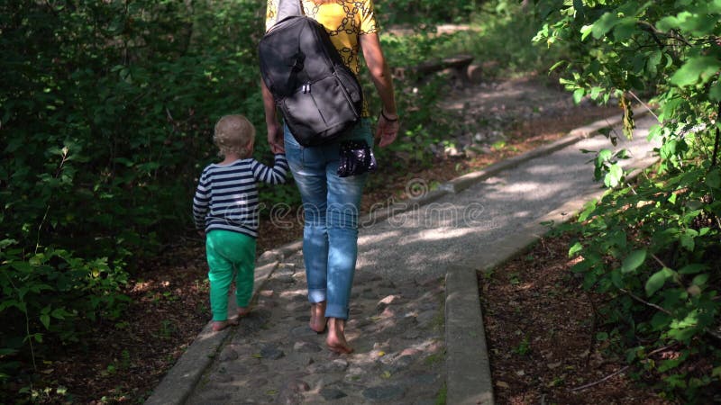 Madre e hijo caminando sobre una piedra pavimentada camino sano en el bosque