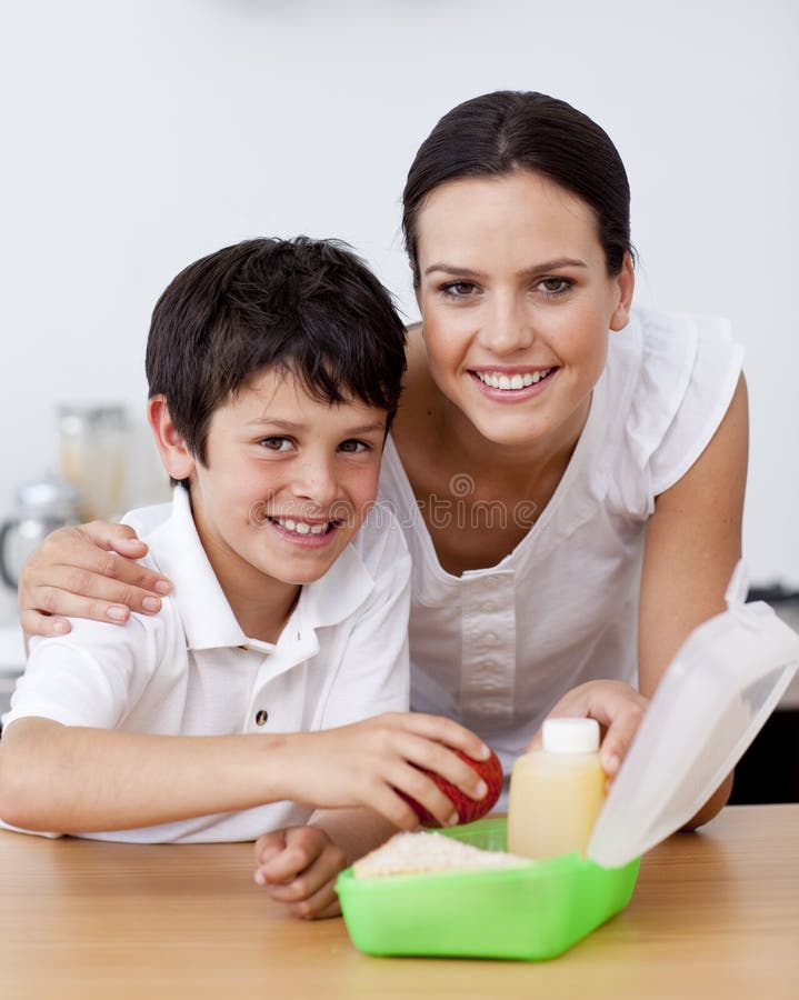 Madre e hijo sonrientes que hacen el almuerzo de escuela foto de archivo libre de regalías Madre e hijo sonrientes que hacen el almuerzo de escuela foto de archivo libre de regalías