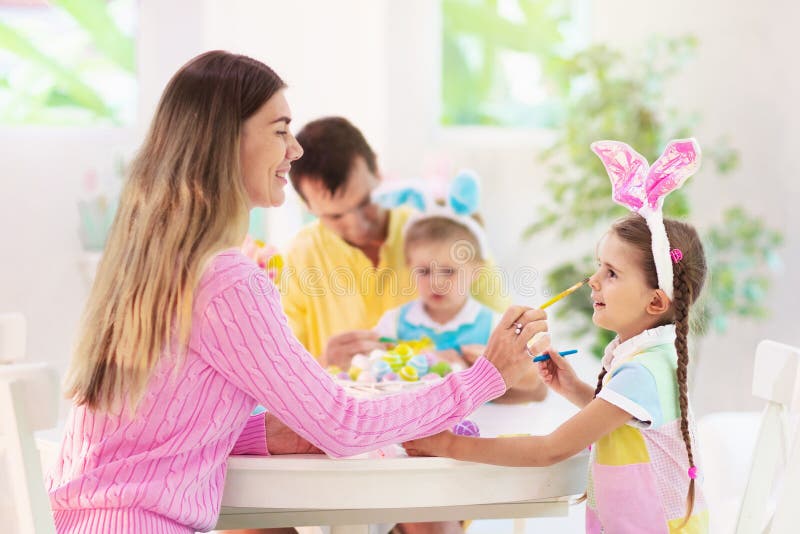 Madre e hijos, coloración familiar Huevos de Pascua. M, padre e hijos color Huevos de Pascua Mamá, papá, niña y niño con orejas de conejo muriendo y pintando para la caza de huevos de Pascua Celebración familiar e infantil Decoración del hogar para las vacaciones de primavera
