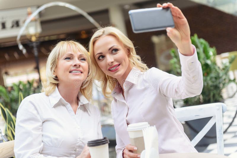 Madre elegante e figlia che prendono colpo sullo smartphone fotografia stock Madre elegante e figlia che prendono colpo sullo smartphone fotografia stock