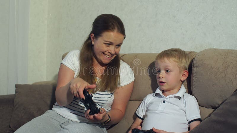 Madre emocionada e hijo que juegan a los videojuegos juntos en casa metrajes