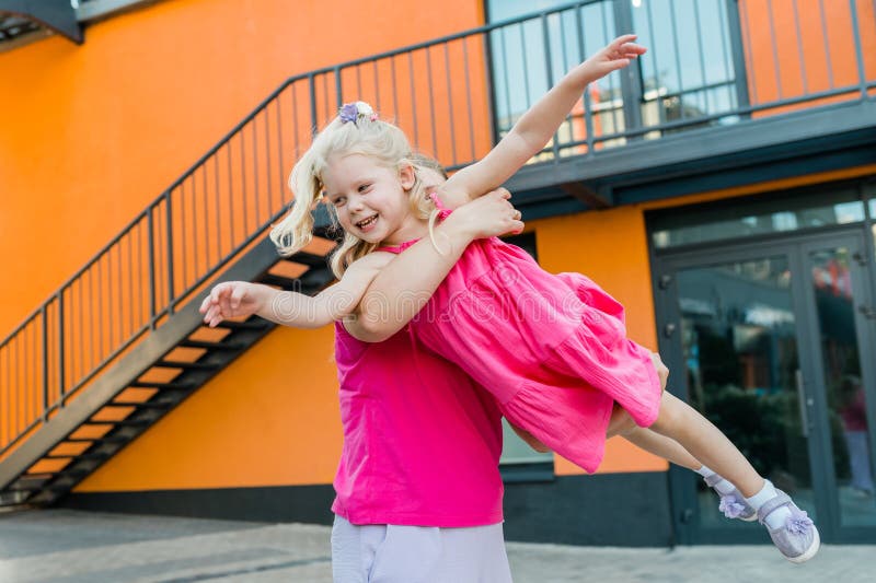 Madre felice che gira e gira una figlia carina in cerchio con le braccia all'aperto. bambino vivace ed energico fotografie stock libere da diritti