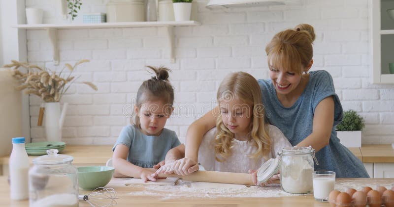 Madre felice che insegna ai bambini che le figlie arrotolano l'impasto in cucina video d archivio