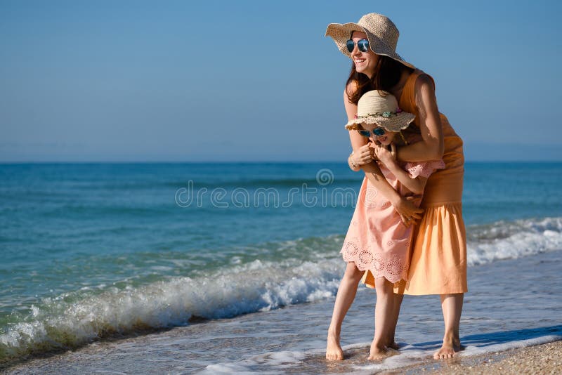 Madre felice e figlia abbracciate in spiaggia fotografia stock libera da diritti