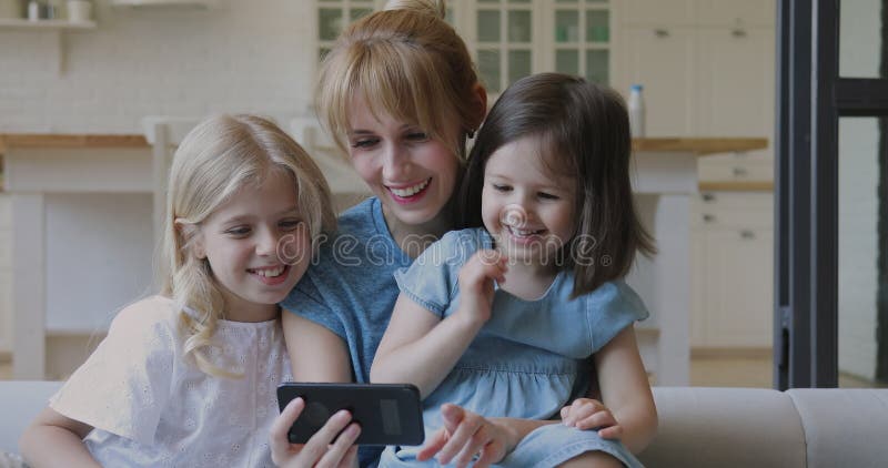 Madre felice e figlie che ridono guardando i cartoni animati su smartphone archivi video