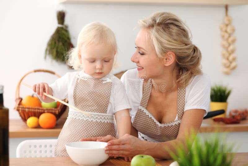 Madre felice e piccola figlia che cucinano nella cucina Spendendo tempo tutto insieme, concetto di divertimento della famiglia immagine stock libera da diritti Madre felice e piccola figlia che cucinano nella cucina Spendendo tempo tutto insieme, concetto di divertimento della famiglia immagine stock libera da diritti