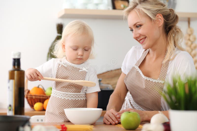 Madre felice e piccola figlia che cucinano nella cucina Spendendo tempo tutto insieme, concetto di divertimento della famiglia fotografie stock Madre felice e piccola figlia che cucinano nella cucina Spendendo tempo tutto insieme, concetto di divertimento della famiglia fotografie stock