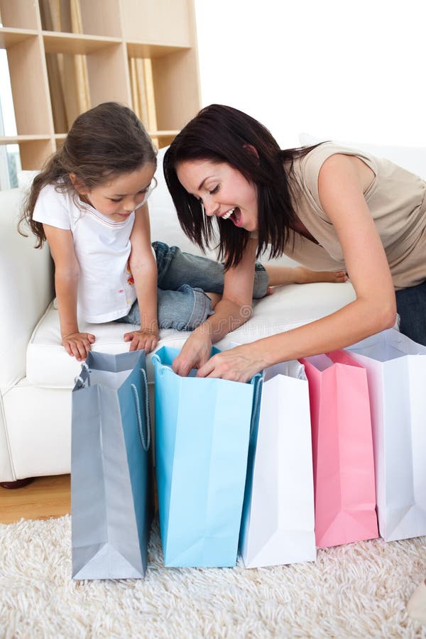 Madre feliz e hija que desempaquetan bolsos de compras imagen de archivo Madre feliz e hija que desempaquetan bolsos de compras imagen de archivo