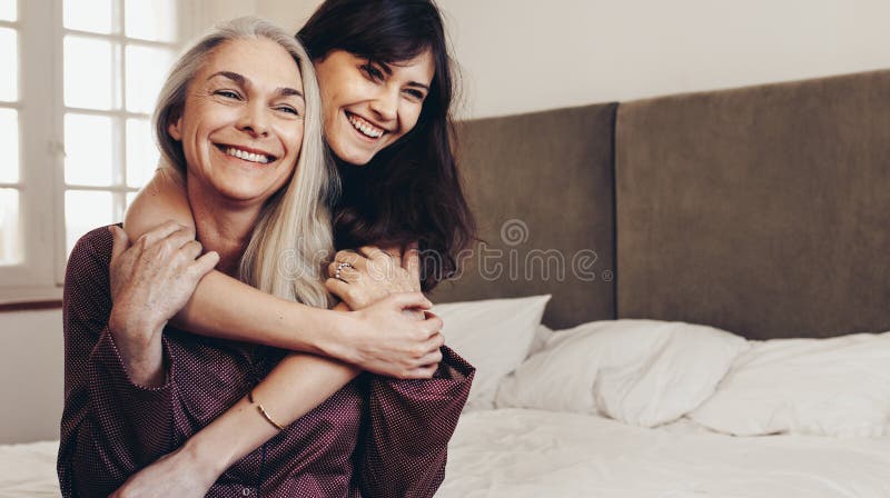 Madre feliz e hija que se sientan en cama en casa fotografía de archivo libre de regalías Madre feliz e hija que se sientan en cama en casa fotografía de archivo libre de regalías