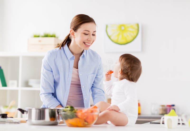 Madre feliz y bebé que comen en casa la cocina fotografía de archivo libre de regalías Madre feliz y bebé que comen en casa la cocina fotografía de archivo libre de regalías