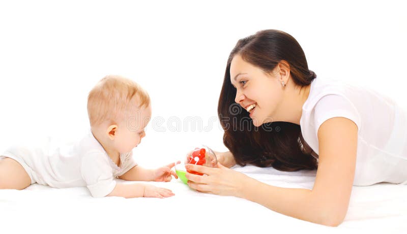 Madre feliz y bebé sonrientes que juegan en juguetes sobre blanco foto de archivo