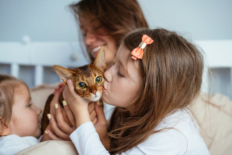 Madre feliz y dos abrazos sonrientes de las hijas en cama foto de archivo libre de regalías Madre feliz y dos abrazos sonrientes de las hijas en cama foto de archivo libre de regalías