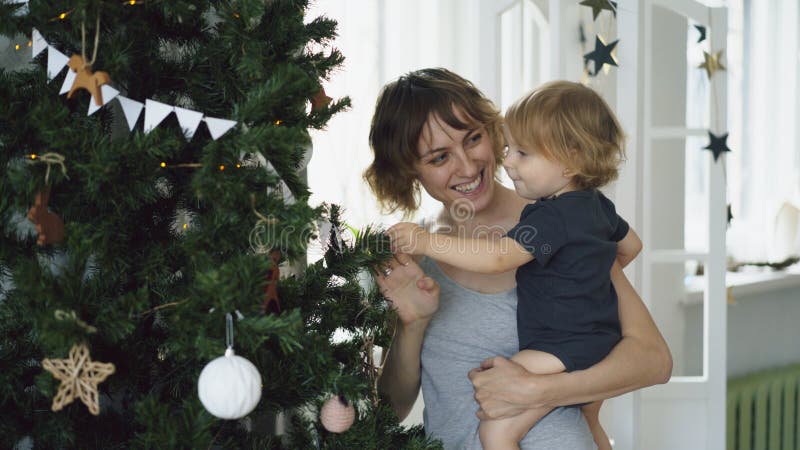 Madre feliz y su pequeña hija que juegan cerca del árbol de navidad en casa imágenes de archivo libres de regalías Madre feliz y su pequeña hija que juegan cerca del árbol de navidad en casa imágenes de archivo libres de regalías