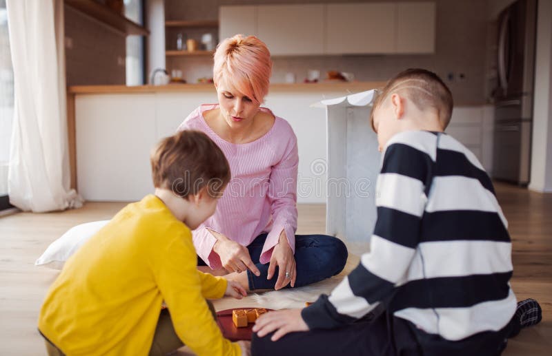 Madre joven con dos niÃ±os jugando juegos de mesa en el suelo