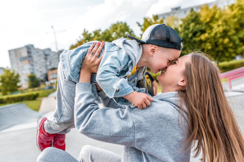 Madre joven juega alegre con niño pequeño en el parque de la ciudad, ropa de otoño en la naturaleza, alegría divertida y emocione imágenes de archivo libres de regalías