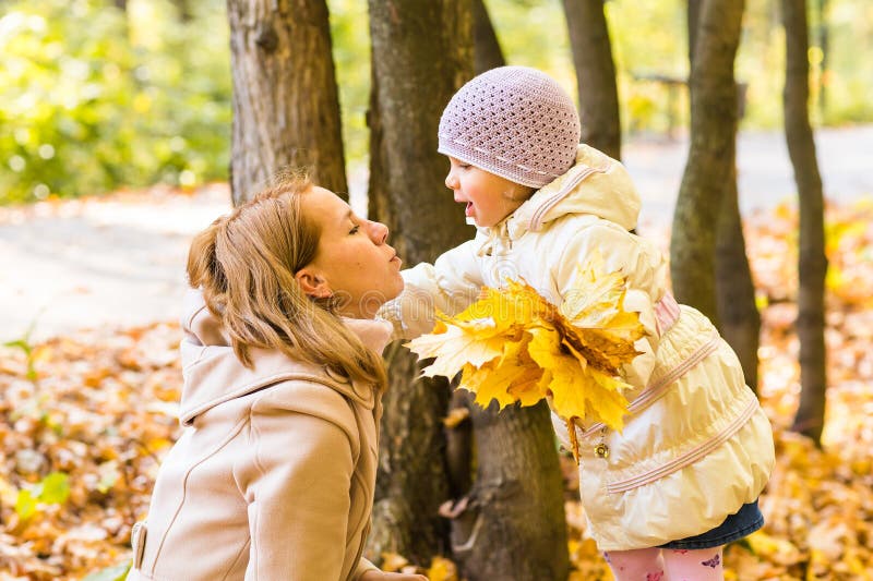 Madre joven que juega con su hija en parque del otoño