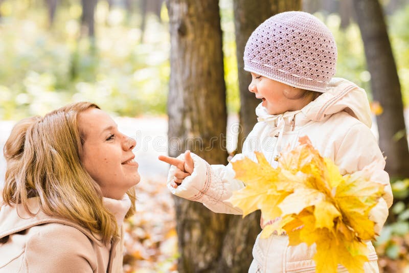 Madre joven que juega con su hija en parque del otoño