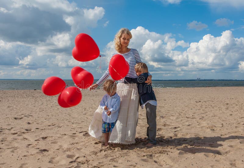 Madre joven y dos hijos que abrazan en la playa fotografía de archivo libre de regalías Madre joven y dos hijos que abrazan en la playa fotografía de archivo libre de regalías