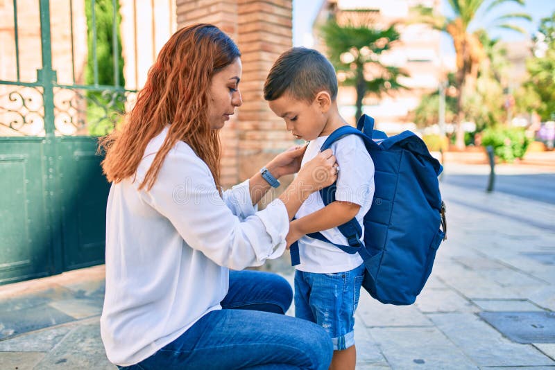 Madre latina monta una mochila a su hijo estudiante en la ciudad fotografía de archivo