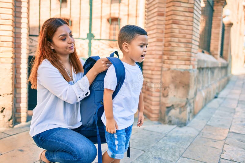 Madre latina monta una mochila a su hijo estudiante en la ciudad fotos de archivo