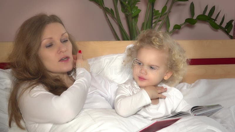 Madre leyendo la historia de la noche a su hija en casa. niñez de maternidad 4k