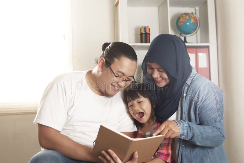 Madre, padre e hijo musulmanes asiáticos están leyendo un libro en casa feliz expresión de emoción foto de archivo libre de regalías Madre, padre e hijo musulmanes asiáticos están leyendo un libro en casa feliz expresión de emoción foto de archivo libre de regalías