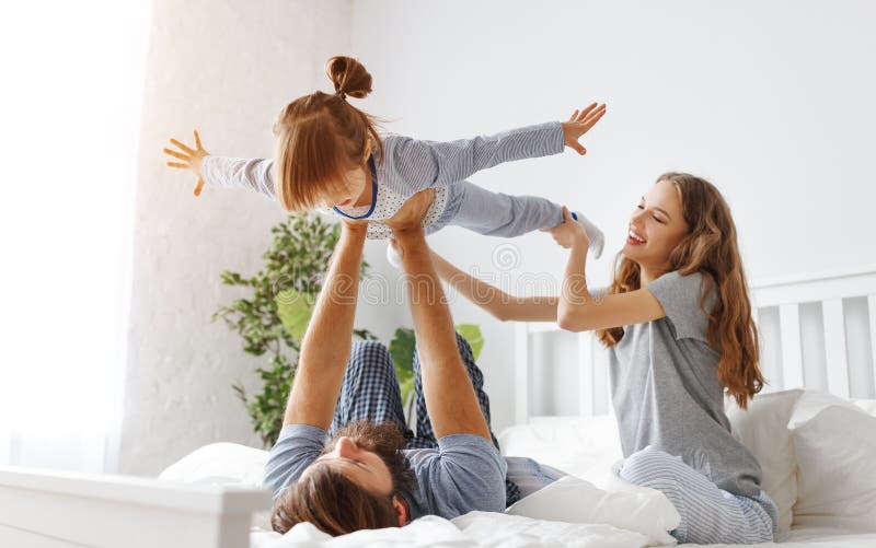 Madre, padre y niño felices de la familia en cama foto de archivo libre de regalías