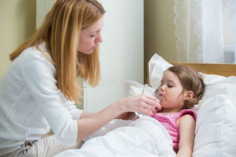 Madre preoccupata che dà medicina al suo bambino malato fotografia stock Madre preoccupata che dà medicina al suo bambino malato fotografia stock