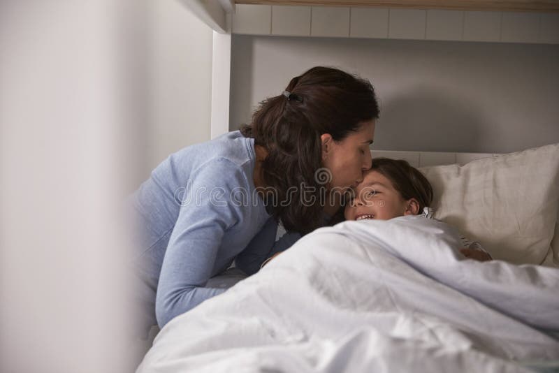 Madre que se besa buenas noches a la hija en la hora de acostarse imagen de archivo libre de regalías Madre que se besa buenas noches a la hija en la hora de acostarse imagen de archivo libre de regalías