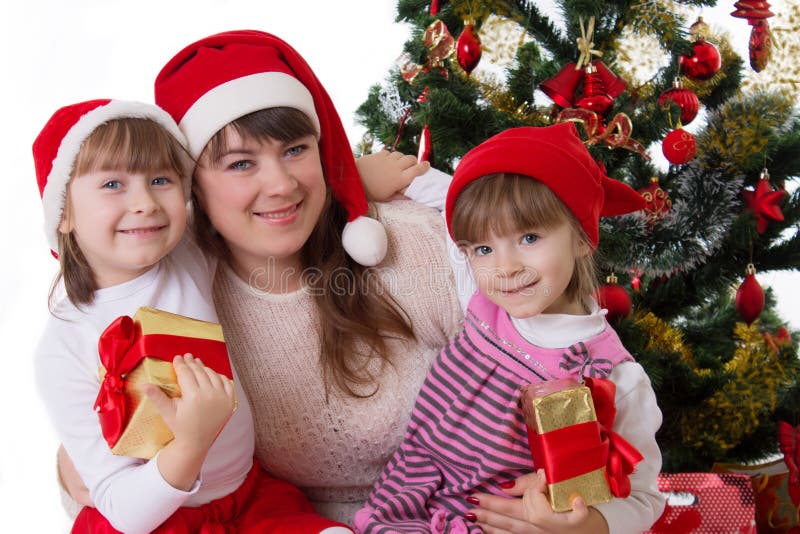 Madre sonriente y dos hijas debajo del árbol de navidad imagen de archivo libre de regalías Madre sonriente y dos hijas debajo del árbol de navidad imagen de archivo libre de regalías