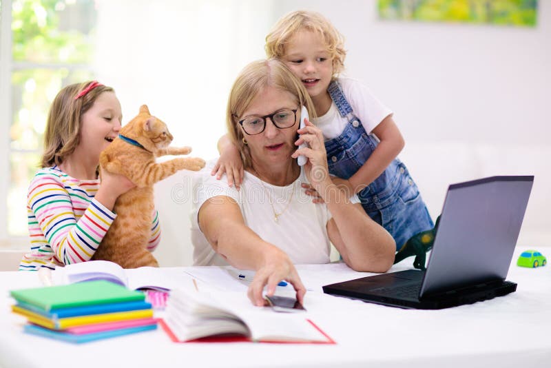 Madre trabajando desde casa con hijos. cuarentena imagen de archivo