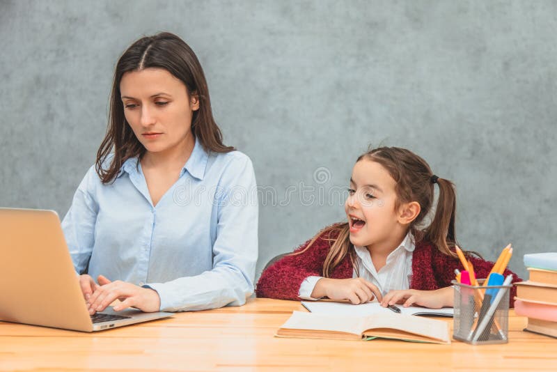 Madre y bebé en un fondo gris Durante esta mujer, el trabajo para un ordenador portátil mira el ordenador portátil Muchacha en ca imágenes de archivo libres de regalías Madre y bebé en un fondo gris Durante esta mujer, el trabajo para un ordenador portátil mira el ordenador portátil Muchacha en ca imágenes de archivo libres de regalías