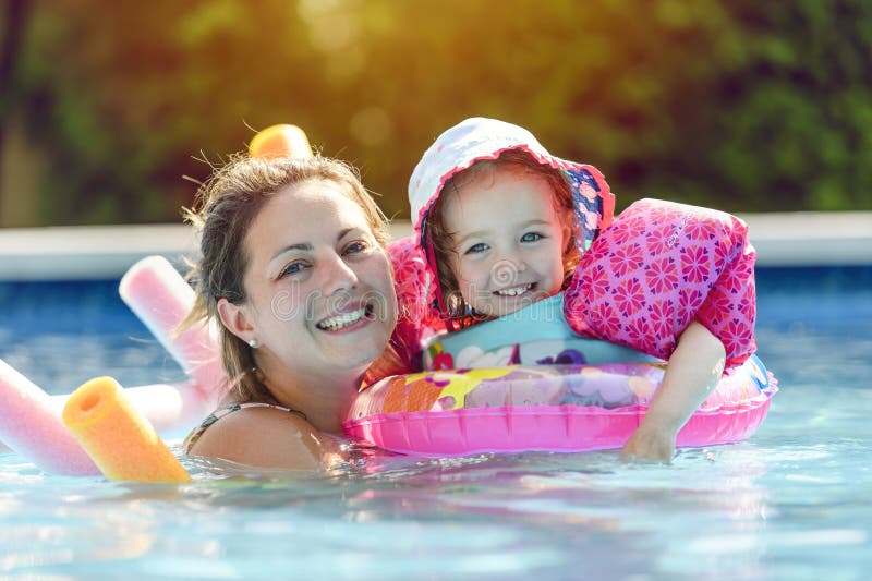 Madre y niña aprenden a nadar en la piscina imagenes de archivo