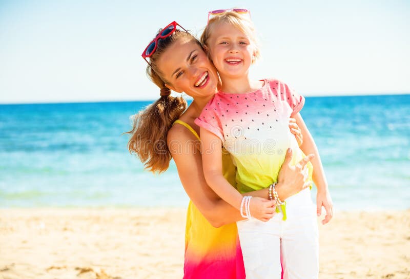 Madre y niño de moda felices en ropa colorida en la costa