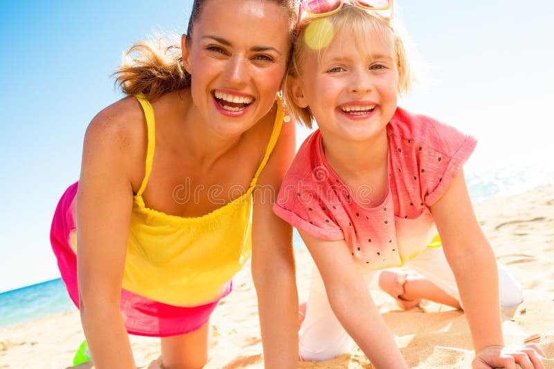 Madre y niño de moda felices en ropa colorida en la playa