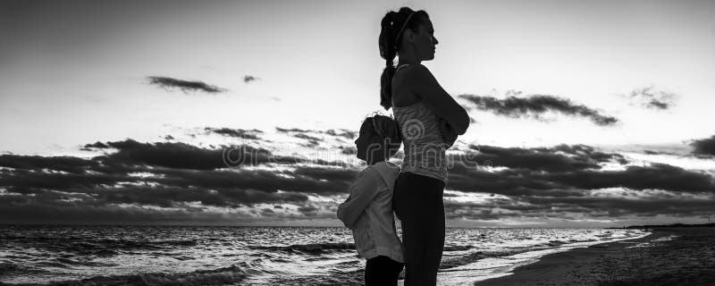 Madre y niño en la playa en la puesta del sol que se coloca de nuevo a la parte posterior fotos de archivo libres de regalías Madre y niño en la playa en la puesta del sol que se coloca de nuevo a la parte posterior fotos de archivo libres de regalías