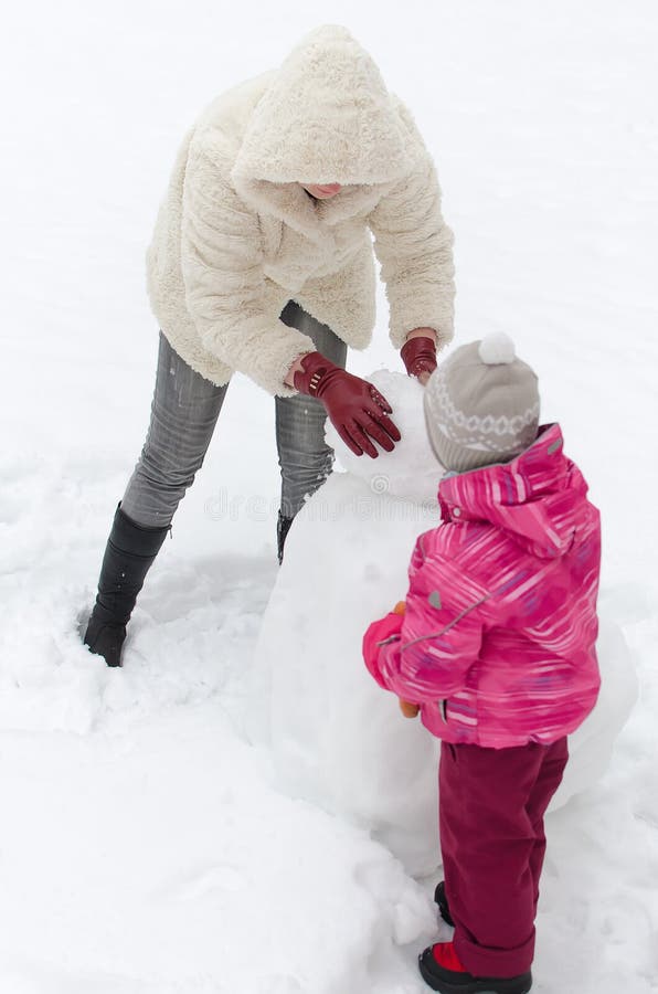 Madre y niño que hacen el muñeco de nieve fotografía de archivo Madre y niño que hacen el muñeco de nieve fotografía de archivo