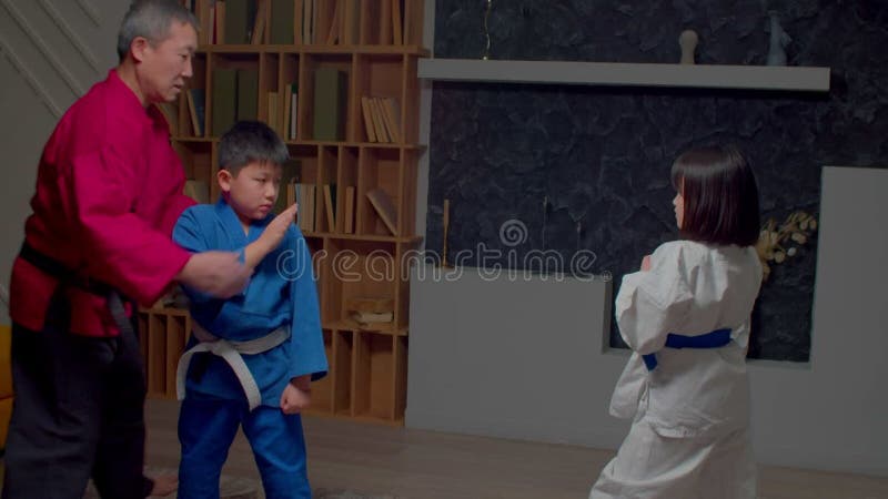 Maestro asiático de taekwondo enseñando a estudiantes preadolescentes a artes marciales metrajes