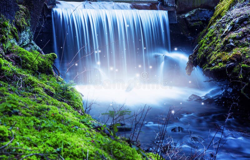 Magic fairytale waterfall with lights in the woods