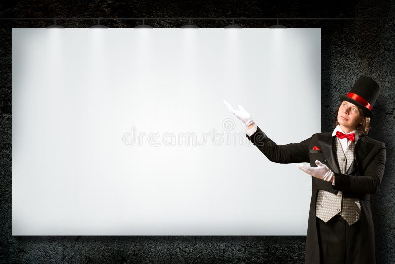 Magician in top hat and tie points to the banner stock photos